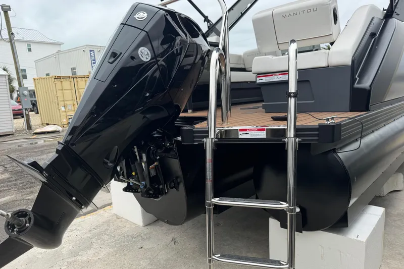 Slide: The Image of 2025 Manitou 24' Explore Switchback boat with powerful outboard motor and ladder. - 3