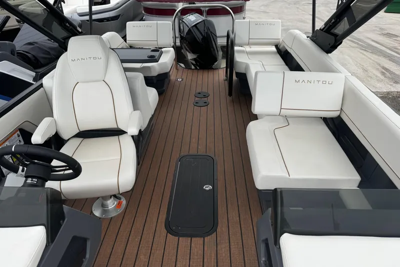 Slide: The Image of 2025 Manitou 24' Explore Switchback boat interior with white seating and wood flooring. - 5