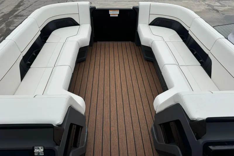 Slide: The Image of 2025 Manitou 24' Explore Switchback boat interior with white seating and wooden flooring. - 8