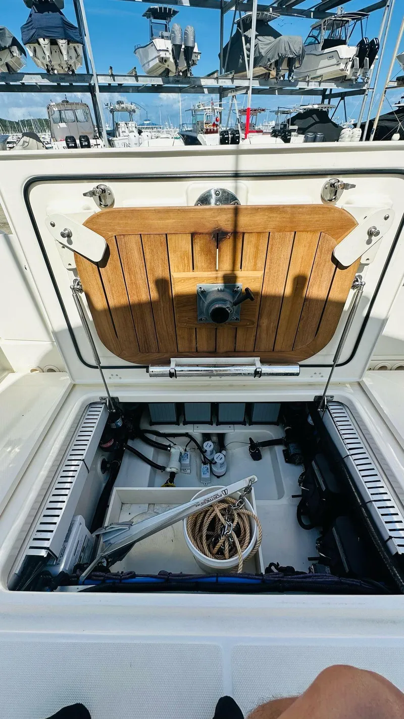 Slide: The Image of 2023 Boston Whaler 330 Outrage storage compartment with open hatch, showcasing interior equipment. - 18