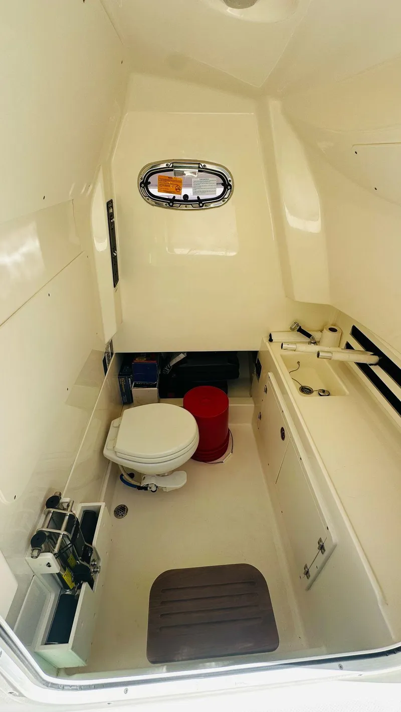 Slide: The Image of 2023 Boston Whaler 330 Outrage cabin interior with toilet and sink. - 24
