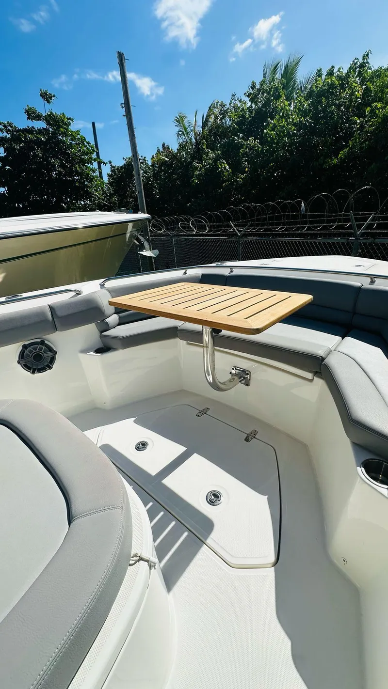 Slide: The Image of 2023 Boston Whaler 330 Outrage boat interior with seating and table under blue sky. - 25