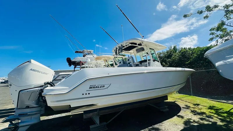The Image of 2023 Boston Whaler 330 Outrage boat with Mercury engines, parked outdoors under blue sky. - 9