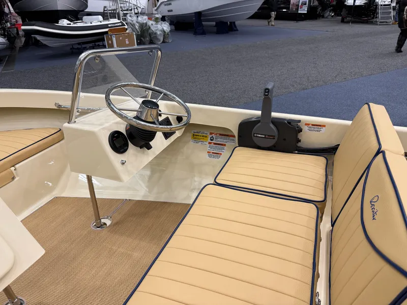 Slide: The Image of 2025 Rossiter 14 boat interior with beige seating and steering wheel at a boat show. - 10