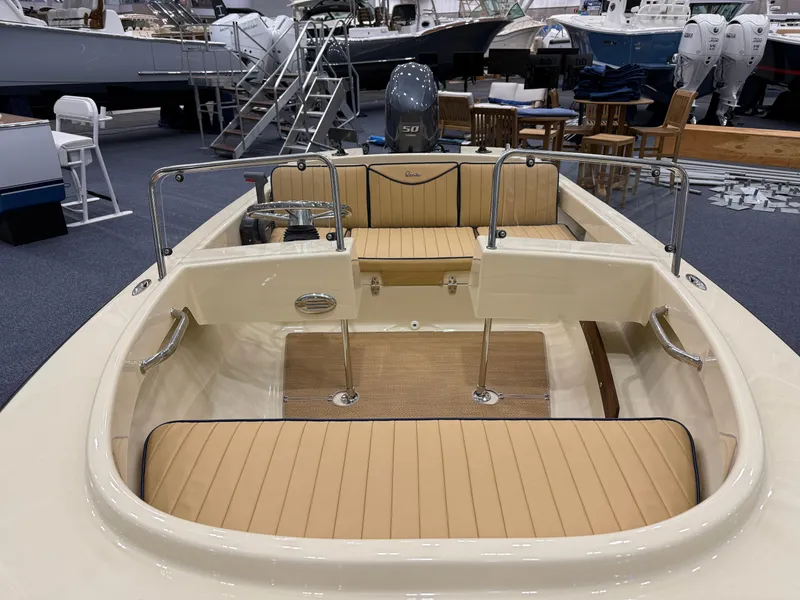 Slide: The Image of 2025 Rossiter 14 boat interior with beige seating and chrome details in a showroom. - 12