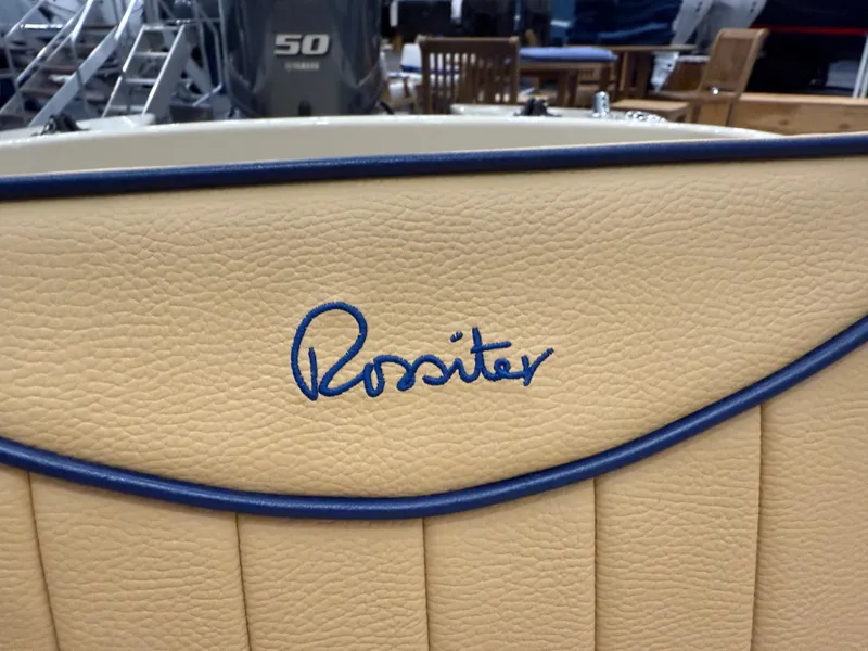 Slide: The Image of Rossiter 14 boat interior detail, 2025 model, featuring beige upholstery with blue stitching. - 15