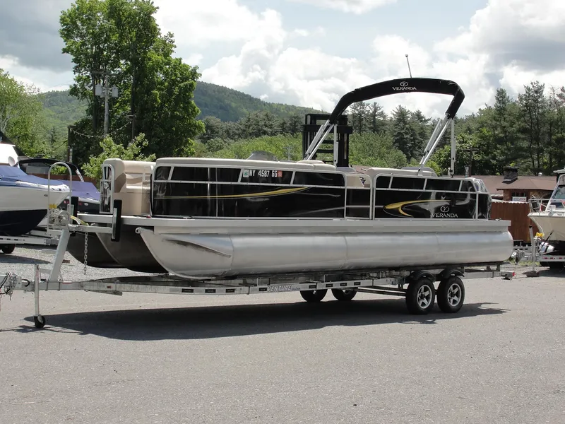Slide: The Image of 2012 Veranda RFL2575V pontoon boat on trailer, parked outdoors with scenic mountain backdrop. - 3