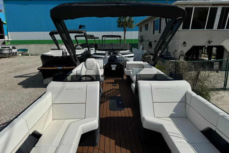 Slide: The Image of 2025 Manitou 24' Explore Switchback boat with white seating and wooden deck. - 2
