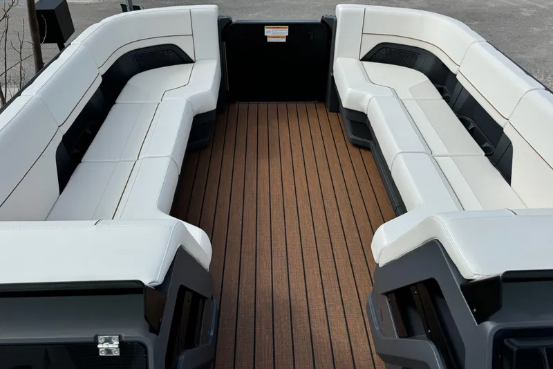 Slide: The Image of 2025 Manitou 24' Explore Switchback boat interior with spacious seating and wood-style flooring. - 3