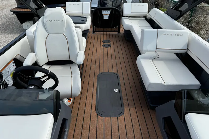 Slide: The Image of 2025 Manitou 24' Explore Switchback boat interior with white seating and wood flooring. - 5