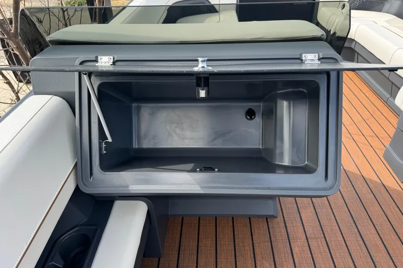 Slide: The Image of 2025 Manitou 24' Explore Switchback boat storage compartment with open lid on deck. - 9