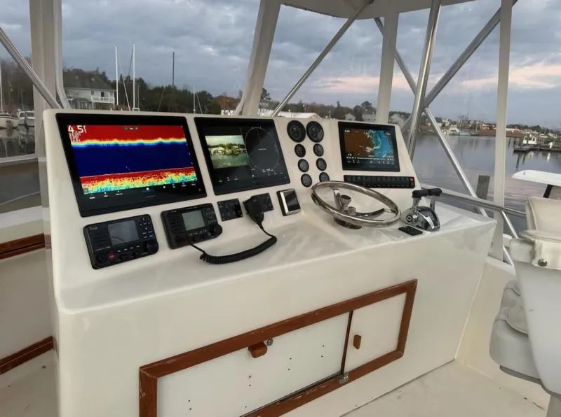 Slide: The Image of 1986 Blackfin 32 Flybridge helm with navigation screens and controls, docked by a marina. - 4