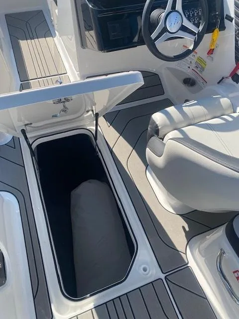 Slide: The Image of 2025 Sea Ray SPX 210 boat interior with open storage compartment and steering wheel. - 7