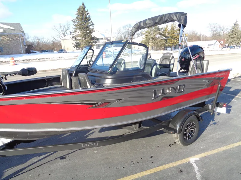 Slide: The Image of 2025 Lund 1875 Impact XS Sport boat, red and gray, parked on a trailer. - 10