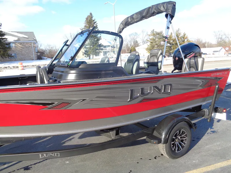 Slide: The Image of 2025 Lund 1875 Impact XS Sport boat, red and black, parked on a trailer. - 12