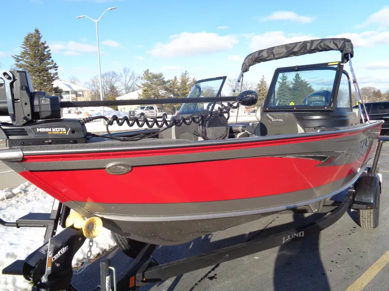 Slide: The Image of 2025 Lund 1875 Impact XS Sport boat, red and black, parked on trailer in snowy setting. - 3