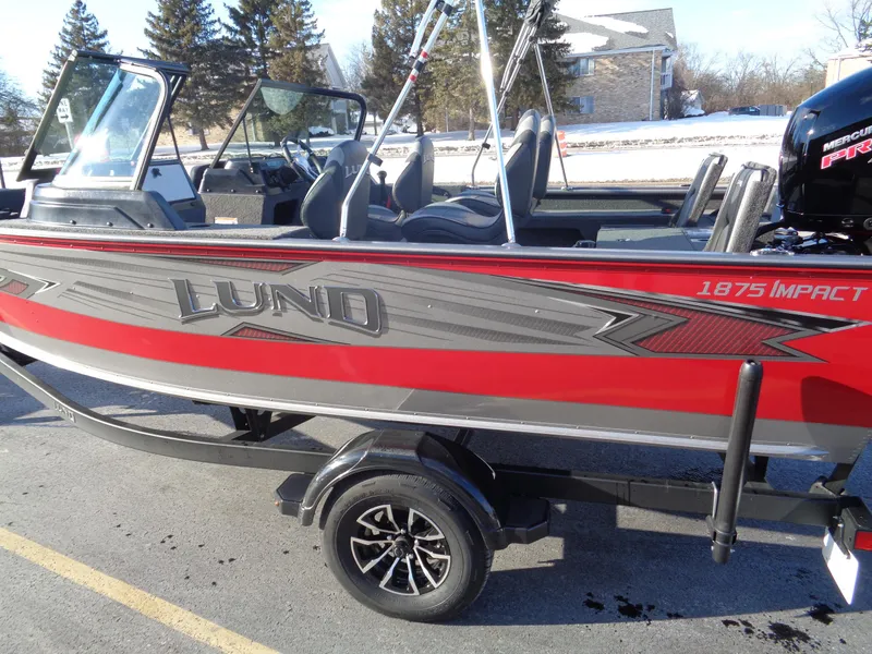 Slide: The Image of 2025 Lund 1875 Impact XS Sport boat, red and gray, parked on a trailer. - 7