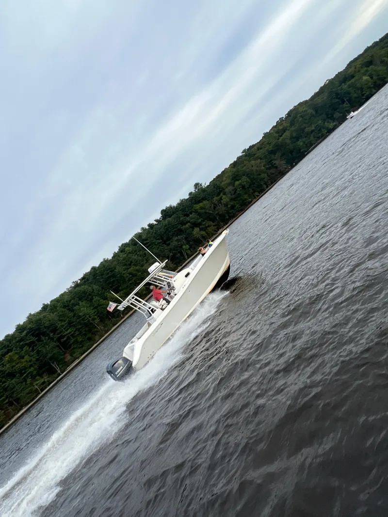 Slide: The Image of 2015 Edgewater 280CC boat cruising on a lake with forested shoreline. - 6