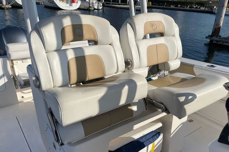 Slide: The Image of 2015 Edgewater 280CC boat seats, beige and white, docked at marina. - 9