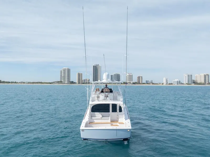 Slide: The Image of 2025 Viking 54 Convertible yacht on open water with city skyline in background. - 34