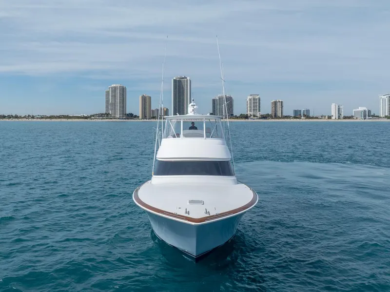 Slide: The Image of 2025 Viking 54 Convertible yacht on open water with city skyline backdrop. - 35