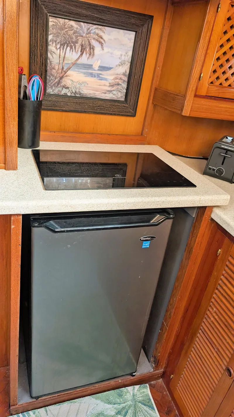 Slide: The Image of Compact kitchen area in a 1986 Heritage East 40 Sundeck boat with fridge and cooktop. - 19