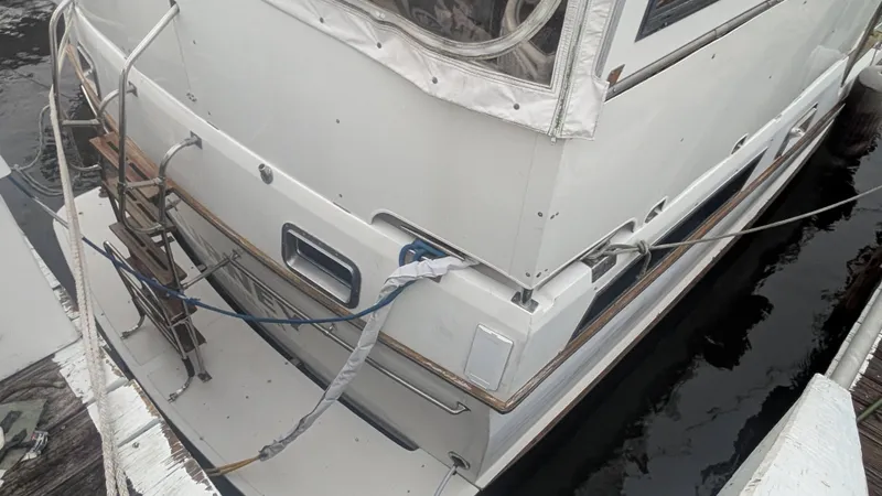 Slide: The Image of 1986 Heritage East 40 Sundeck yacht docked, featuring a swim platform and boarding ladder. - 2