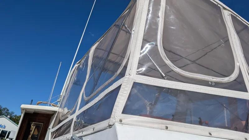 Slide: The Image of 1986 Heritage East 40 Sundeck boat with clear enclosure against blue sky. - 4