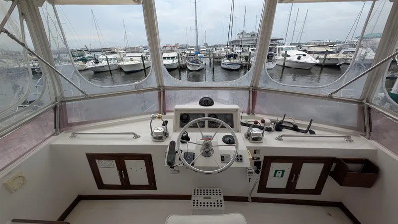 Slide: The Image of 1986 Heritage East 40 Sundeck helm with marina view, showcasing steering wheel and controls. - 50