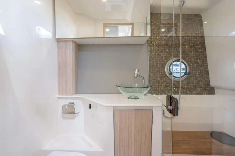 Slide: The Image of Modern bathroom interior in 2025 Hanover 377 Outboard yacht, featuring glass sink and porthole window. - 18