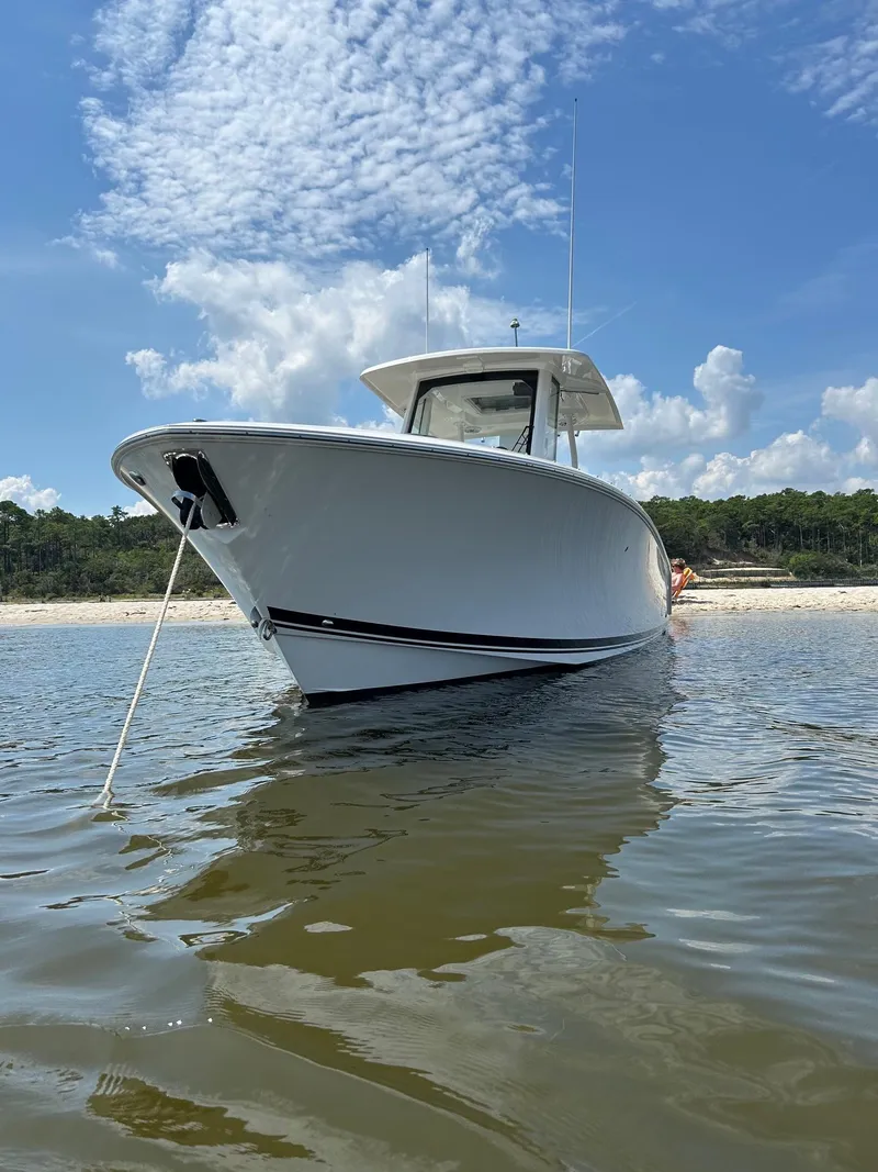 Slide: The Image of 2023 Pursuit S 288 Sport boat anchored near a sandy beach under a blue sky. - 34