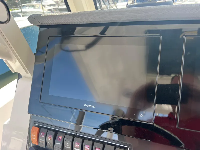 Slide: The Image of Garmin display on 2023 Pursuit S 288 Sport boat dashboard with control switches. - 43