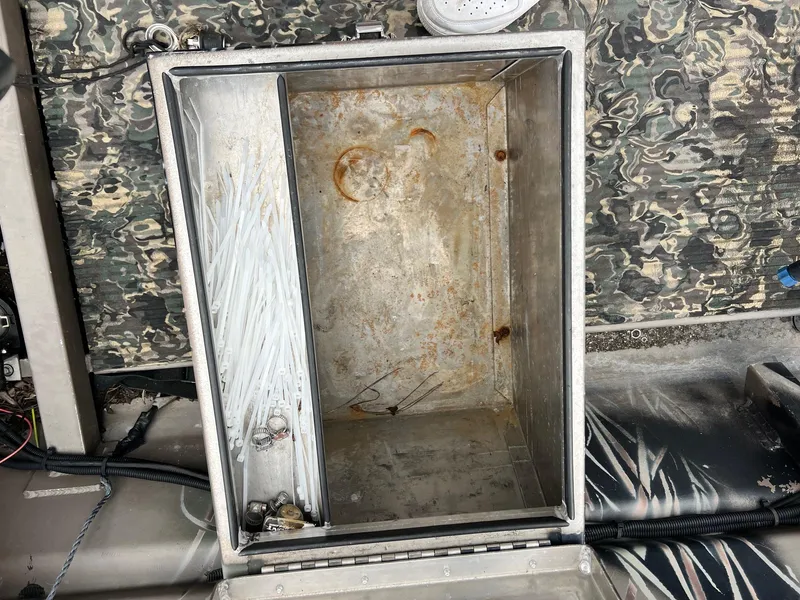 Slide: The Image of Open storage compartment in a 2012 Pro-Drive 1854 boat, showing zip ties and metal clamps. - 4