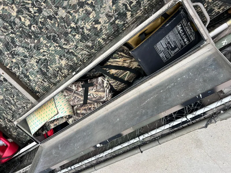 Slide: The Image of Storage compartment in a 2012 Pro-Drive 1854 boat with camo gear and accessories. - 7