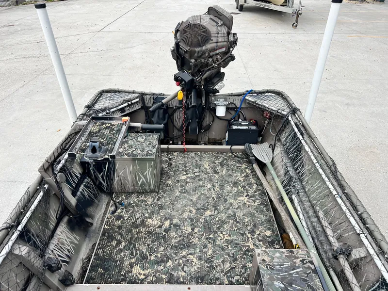 Slide: The Image of 2012 Pro-Drive 1854 boat interior with camouflage design and motor, parked on concrete. - 9