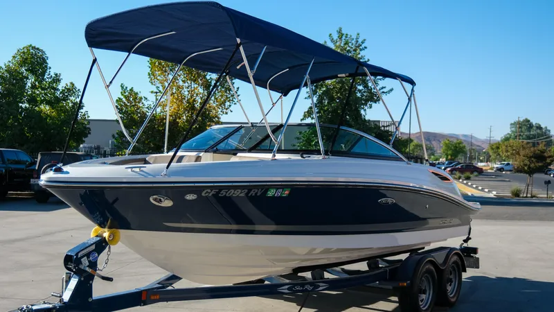 Slide: The Image of 2013 Sea Ray 210 SLX boat on trailer with canopy, parked outdoors. - 2