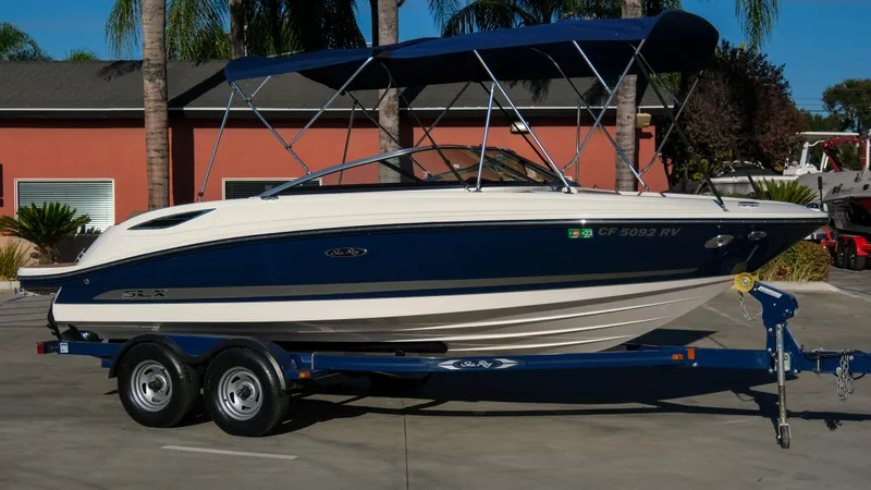 Slide: The Image of 2013 Sea Ray 210 SLX boat on trailer, parked outdoors. - 6