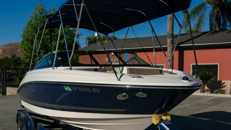 Slide: The Image of 2013 Sea Ray 210 SLX boat with canopy, parked on a trailer in a sunny setting. - 8