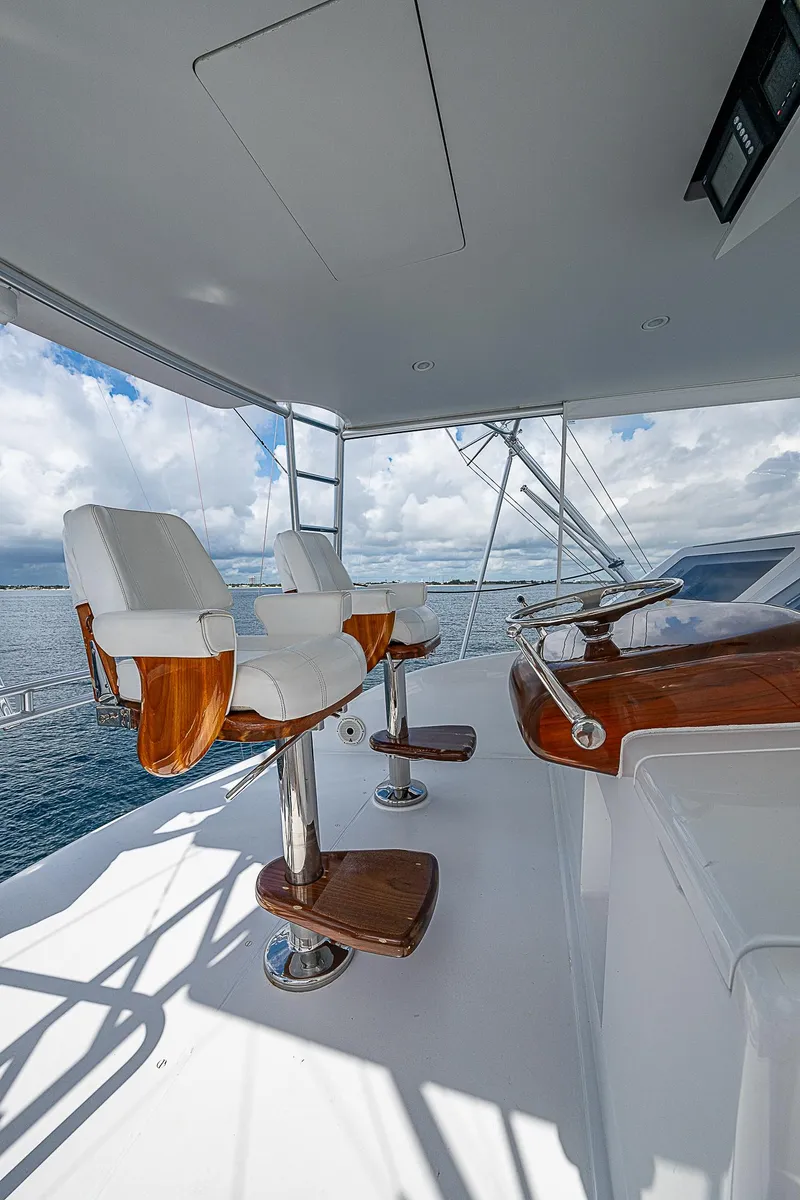 Slide: The Image of 2003 Viking Convertible yacht helm with white chairs and wooden accents on open deck. - 14
