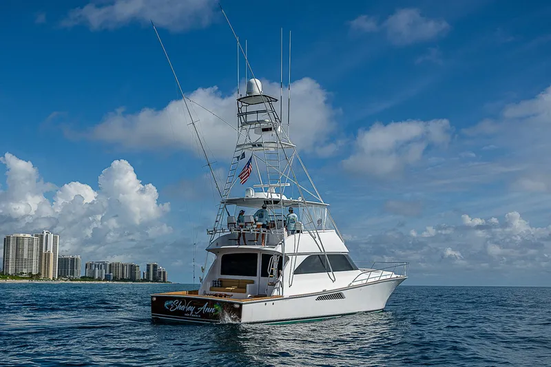 Slide: The Image of 2003 Viking Convertible yacht on ocean, city skyline in background, clear blue sky. - 6