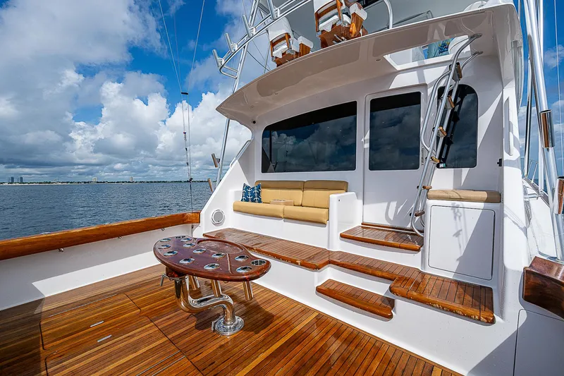 Slide: The Image of 2003 Viking Convertible yacht deck with wooden flooring and seating, overlooking calm waters. - 8