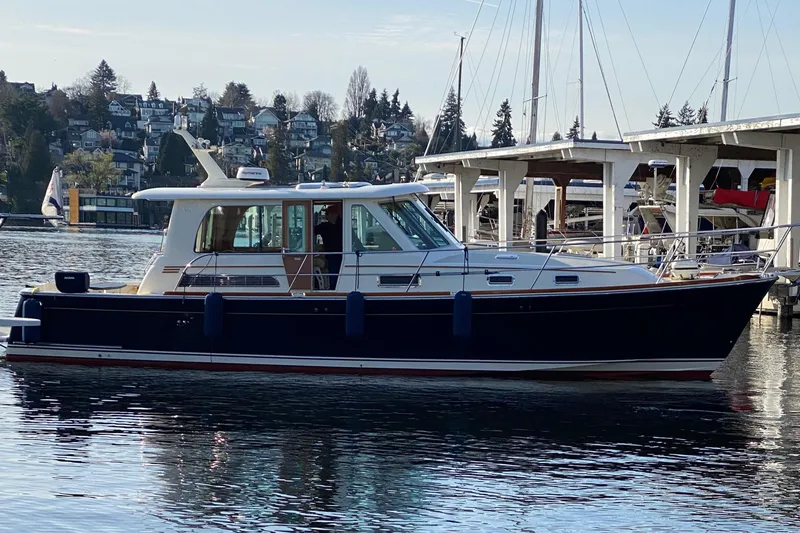 Slide: The Image of 2011 Sabre 42 Salon Express yacht docked in a marina, calm water, scenic background. - 2