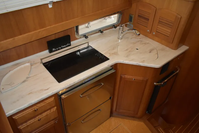 Slide: The Image of 2011 Sabre 42 Salon Express galley with stove, sink, and wooden cabinetry. - 40