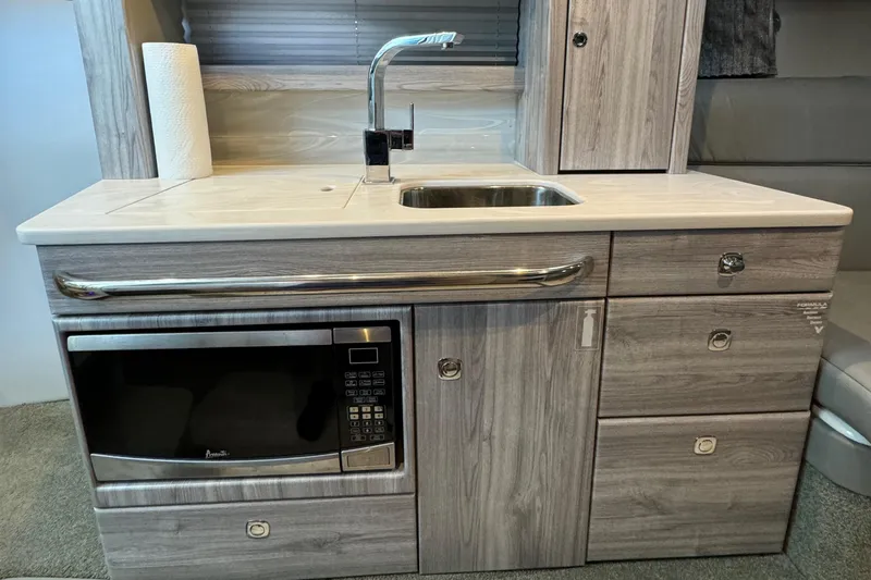 Slide: The Image of 2020 Formula 370 SS kitchenette with sink, microwave, and storage cabinets. - 28