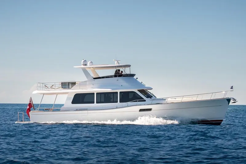 Slide: The Image of 2026 Grand Banks GB 60 yacht cruising on open sea under clear blue sky. - 0
