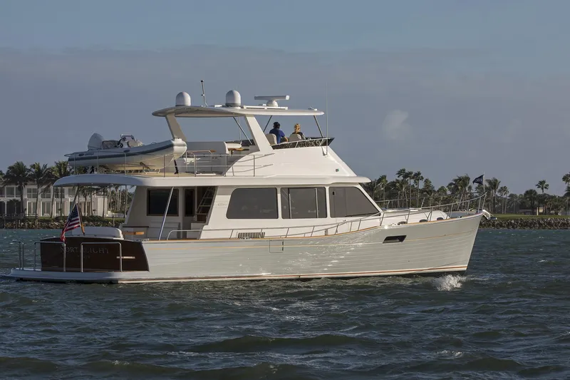 Slide: The Image of 2026 Grand Banks GB 60 yacht cruising on open water, with clear skies and distant shoreline. - 16