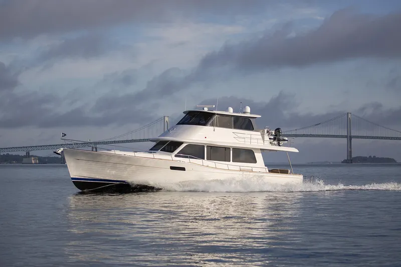 Slide: The Image of 2026 Grand Banks GB 60 yacht cruising near a bridge on a cloudy day. - 23