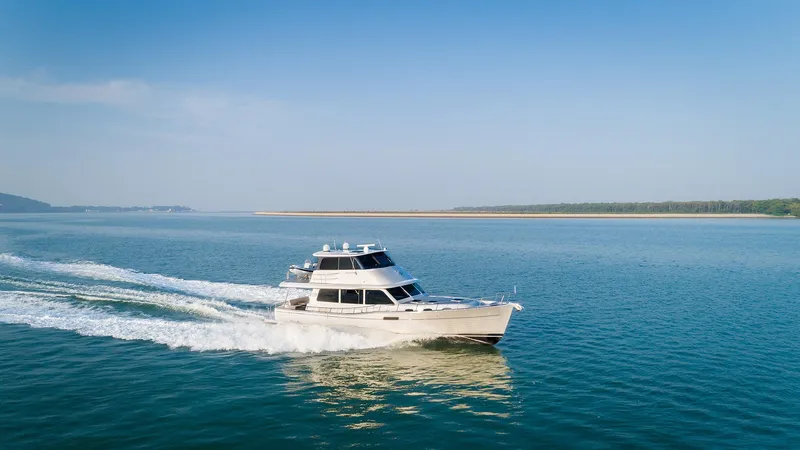 Slide: The Image of 2026 Grand Banks GB 60 yacht cruising on open water under clear blue skies. - 28