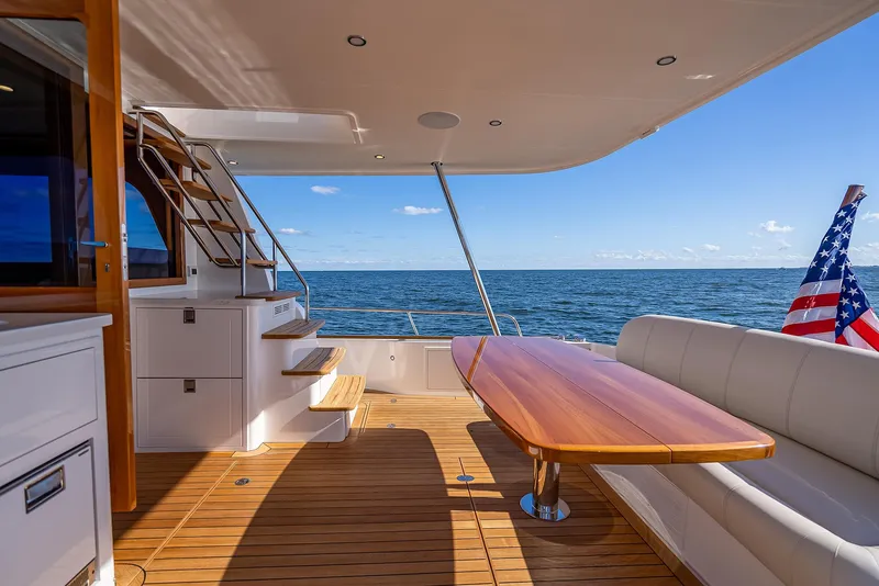 Slide: The Image of 2026 Grand Banks GB 54 yacht deck with seating, table, and ocean view. - 8
