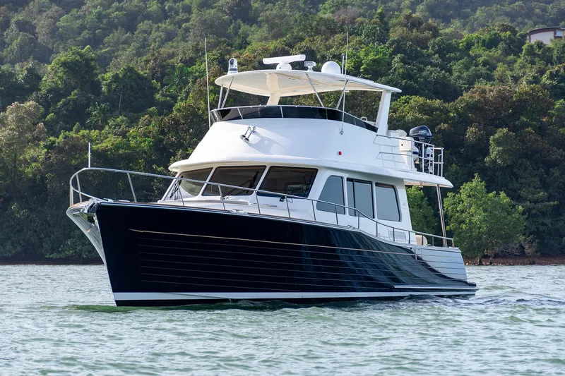 Slide: The Image of 2026 Grand Banks GB 54 yacht cruising on a serene lake with lush green backdrop. - 1